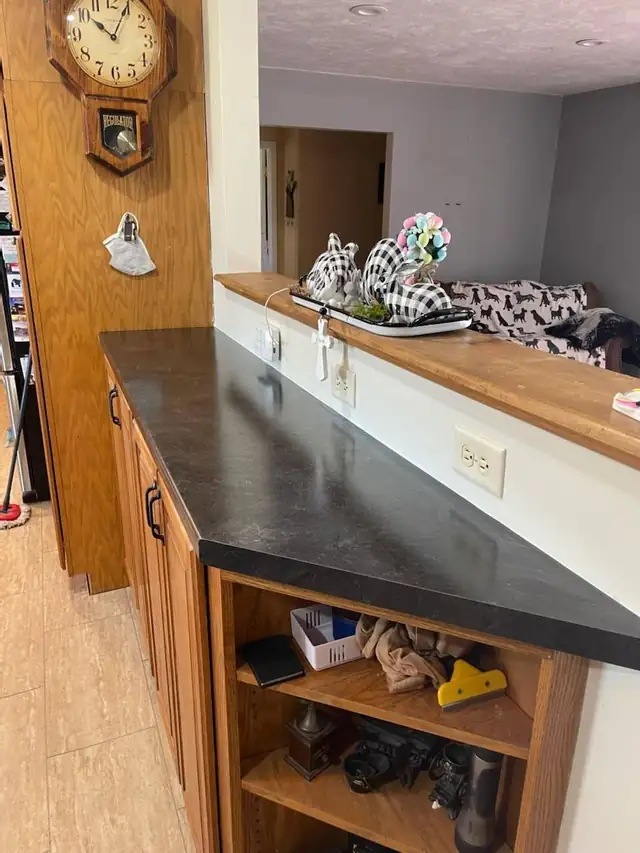 Dark slate-look laminate countertop with an angled end on an oak cabinet peninsula